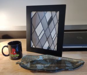 A dinosaur coffee mug, framed art, and a banana leaf tray